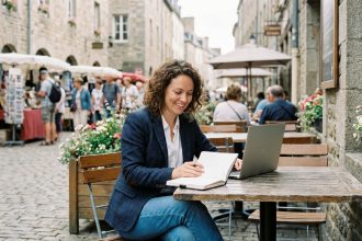 Femme souriante avec ordinateur dans un café européen